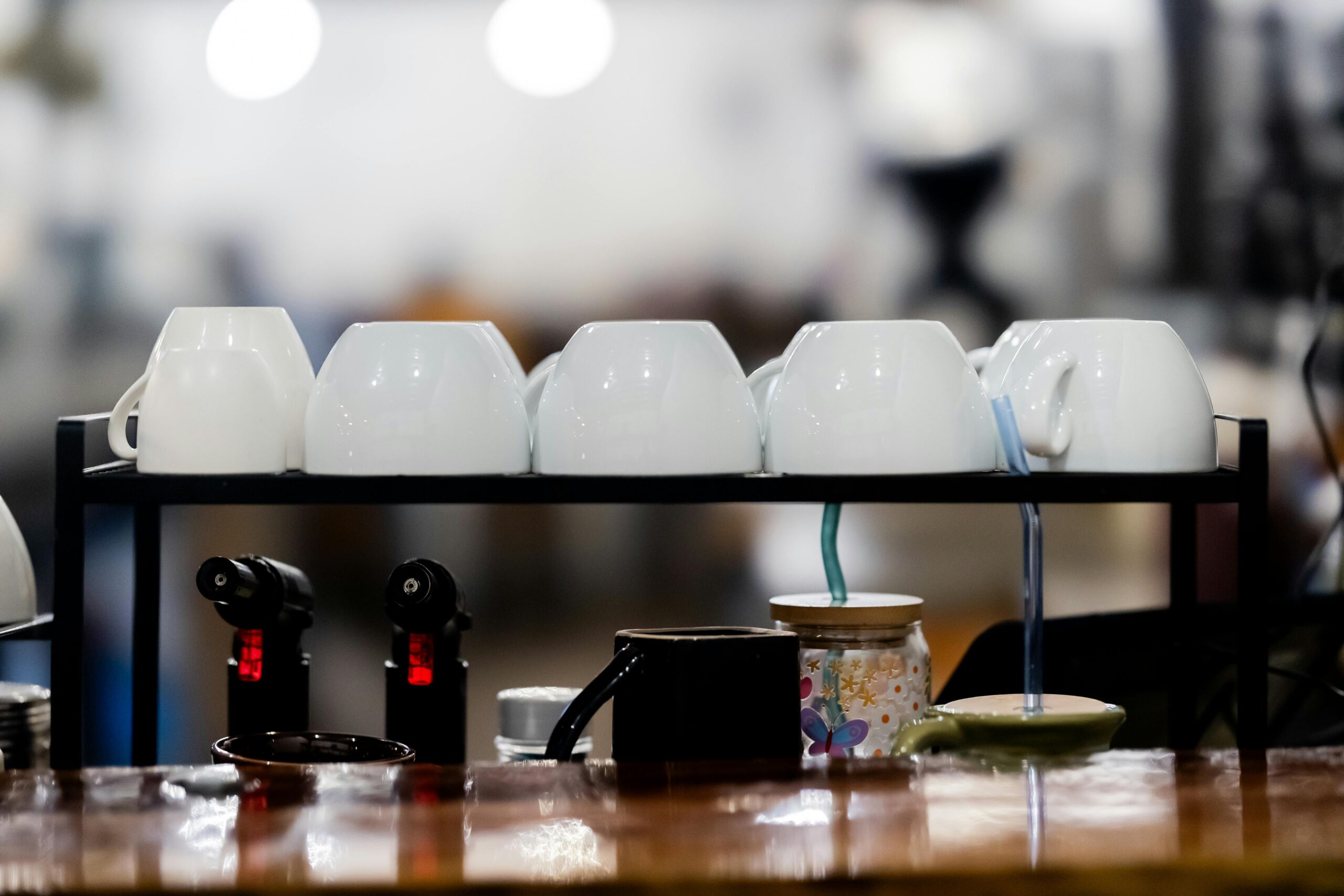 A row of white coffee cups stacked on a café counter shelf, creating a clean and minimalist look.